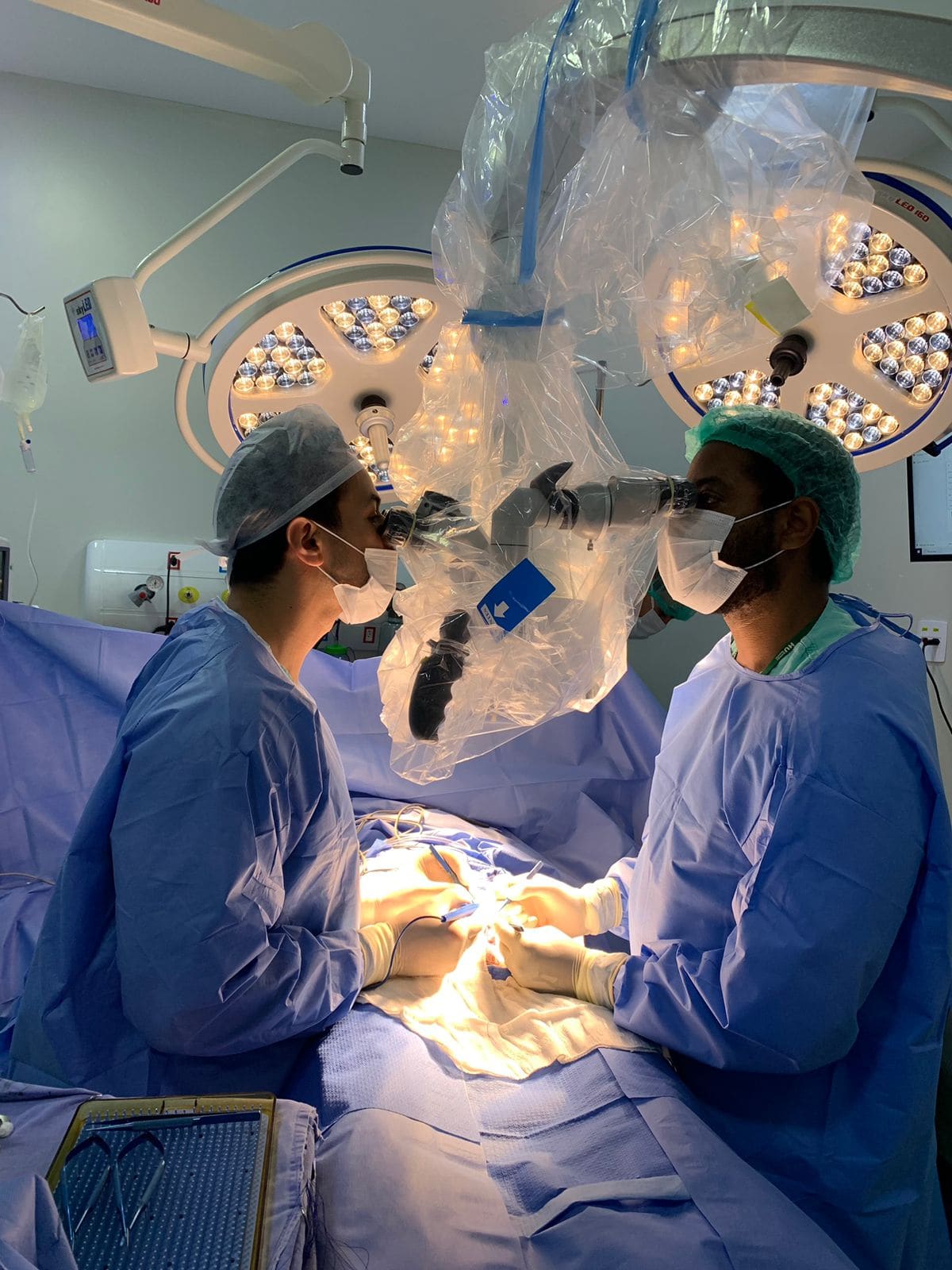 Dr. Juan Mendes operando ao microscópio cirúrgico — microcirurgia